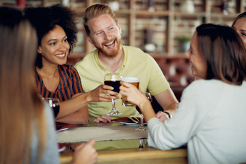 Friends making a toast while sitting in restaurant. Multi-ethnic group.