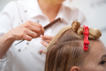 Fototapeta premium Professional hairdresser making a hairdo to a fair-haired model