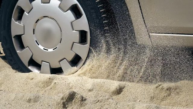 Spinning wheel of a car stuck in the sand on a sea beach