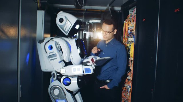 Engineer works with a robot in a server room, close up.