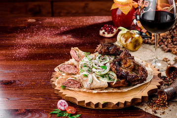 Georgian cuisine. grilled meat with onions, pita bread with sausages and a glass of rad wine on a wooden board on a burlap. top view. flat lay. close-up.