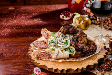 Georgian cuisine. grilled meat with onions, pita bread with sausages and a glass of rad wine on a wooden board on a burlap. top view. flat lay. close-up.