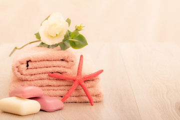 Stack of soft terry towels with soap and flower on wooden boards