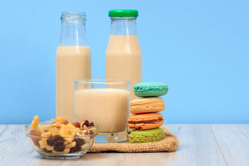 Bottles and glass of milk, bowl with muesli, macaroons on sackcloth.