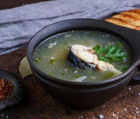 fish soup of mackerel in a brown clay plate on a wooden board