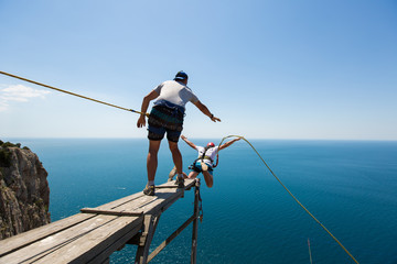 Rope jumping off a cliff with a rope in the water. The ocean. Sea. Mountain