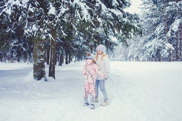 happy family mother and child daughter having fun, playing at winter forest outdoors