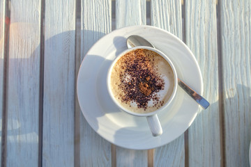 cup of cappuccino with latte art on wooden white table. top view
