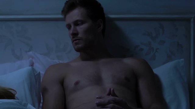 Thoughtful husband lying in bed, man keeping secret from his wife, remorse