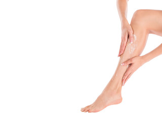 Female hands applying cream on the skin of her leg, close up