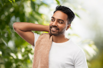 grooming and people concept - smiling indian man with bath towel over green natural background