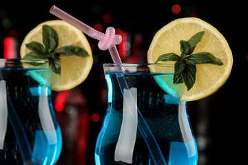 Cocktail blue lagoon in a cocktail glass with lemon and mint on a brown wooden table in the bar.