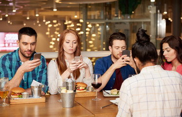 leisure, technology, lifestyle and people concept - friends with smartphones dining at restaurant