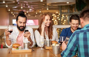 leisure and people and concept - friends having dinner and drinking red wine at restaurant