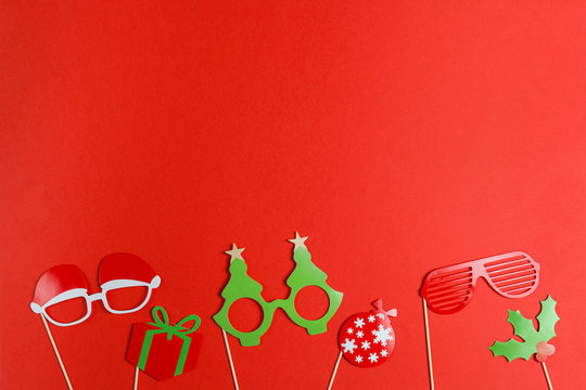 A Christmas party props for a photo booth on red background - funny glasses, ball, gift. Flat lay, copy space. - Powered by Adobe