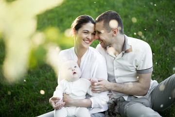 Portrait Beautiful Mother, Father And Baby outdoors. Happy family on a summer meadow