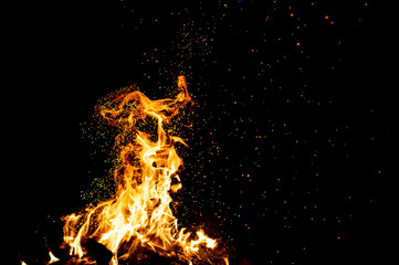 Burning woods with firesparks, flame and smoke. Strange weird odd elemental fiery figures on black background. Coal and ash. Abstract shapes at night. Bonfire outdoor on nature. Strenght of element.