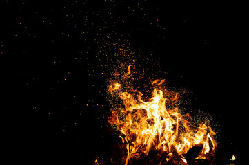 Fototapeta na wymiar Burning woods with firesparks, flame and smoke. Strange weird odd elemental fiery figures on black background. Coal and ash. Abstract shapes at night. Bonfire outdoor on nature. Strenght of element.