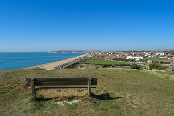 Naklejka na ściany i meble An empty park bench on Seaford Head Sussex UK, overlooking the town on a sunny day