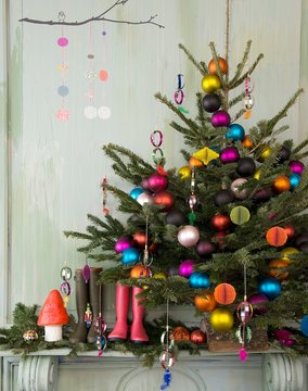 Christmas tree with multicoloured baubles, wellington boots and festive ornaments on mantelpiece