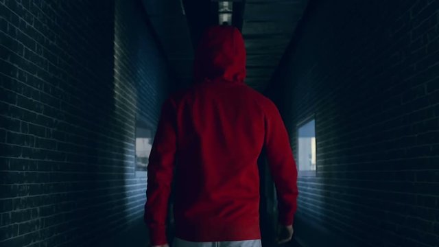 Guy in the red capuche walking in the dark hallway.