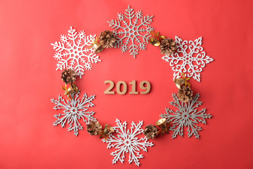Fototapeta na wymiar The inscription 2019 in a frame of snowflakes and Christmas decor on a red background. view from above