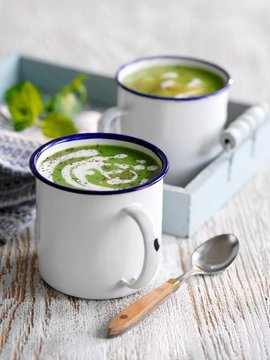 Cream of pea soup with mint in enamel mugs