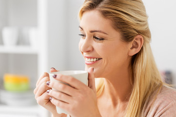 leisure, drink and people concept - close up of happy young woman with cup of coffee at home