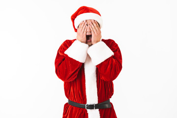 Portrait of scared man 30s in santa claus costume and red hat grabbing face, isolated over white background in studio