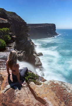 Woman watches waterfall flows off cliffs into ocean