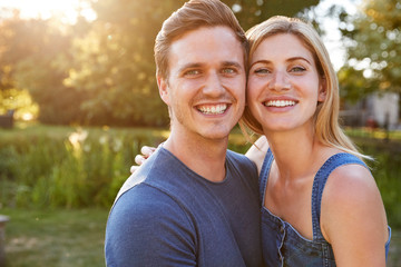 Obraz premium Portrait Of Smiling Couple Outdoors In Summer Park Against Flaring Sun