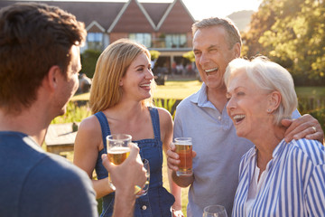 Parents With Adult Offspring Enjoying Outdoor Summer Drink At Pub