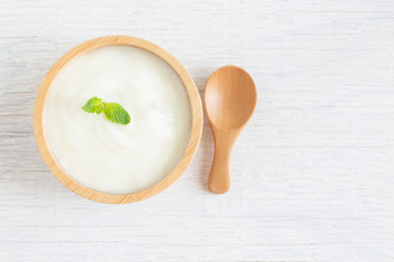 Yogurt in wood bowl on white wooden table Healthy food concept, top view and copy space