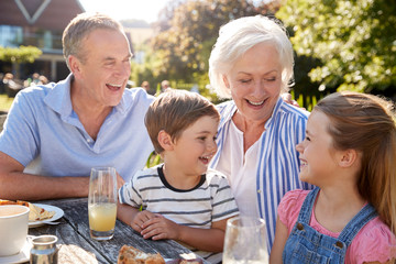 Grandparents With Grandchildren Enjoying Outdoor Summer Snack At Cafe