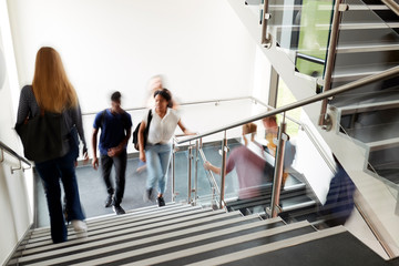 Motion Blur Shot Of High School Students Walking On Stairs Between Lessons In Busy College Building