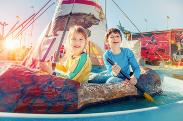 Children having fun at amusement park.  Ride on canoe. Happy childhood concept.