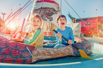 Children having fun at amusement park.  Ride on canoe. Happy childhood concept.