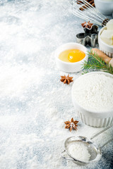 Obraz na płótnie Canvas Christmas and winter baking background. Kitchen utensils and ingredients for cooking baking - flour, sugar, eggs, butter, milk, cinnamon sticks, whisk, rolling pin, anise, Blue concrete background 