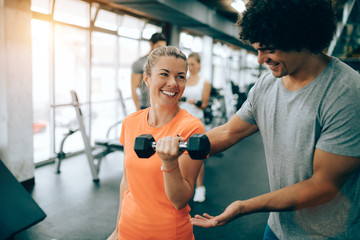 Personal trainer assisting beautiful woman lose weight