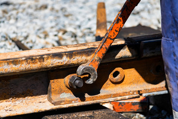 Worker tightens the skrew in railway or tram tracks