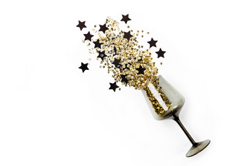 Black wine glasses with golden confetti and black stars on white background. Flat lay, top view. Holyday and celebration concept.