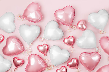 Air Balloons of heart shaped foil  on pastel pink background. Love concept. Holiday celebration....