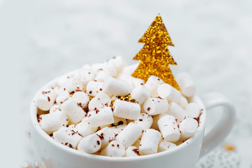 Coffee cups with marshmallow and shiny gold decorative Christmas tree. Christmas decor and gifts