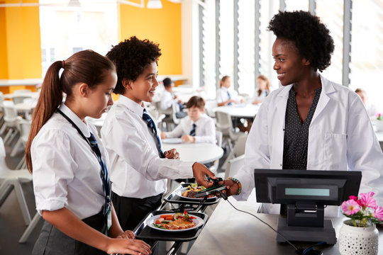 High School Students Wearing Uniform Paying For Meal In Cafeteria