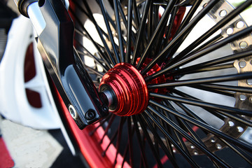 Chopper motorcycle wheel closeup with a pattern of shiny black spokes.