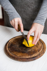 Woman cuts lemon into slices close view