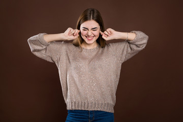 Close up portrait of angry stressed out young woman plugging ears with fingers, irritated with loud annoying noise, having headache or migraine. Negative human emotions