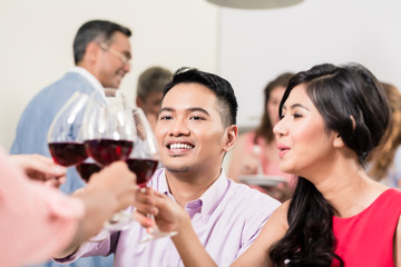 Smiling young couple toasting wineglasses with friends
