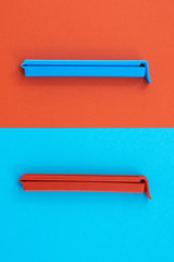 Plastic sealing clip on red and blue background.