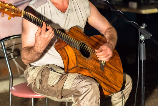 Man playing yellowe an acoustic guitar closeup
